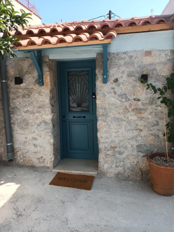 uma porta verde numa casa de pedra com telhado de azulejo em Apartment Rustico em Ancient Epidavros