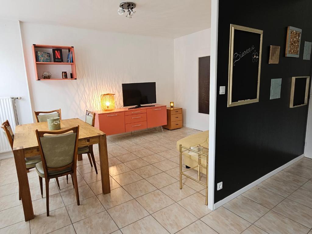 ein Wohnzimmer mit einem Tisch und einem TV in der Unterkunft Appartement in Troyes