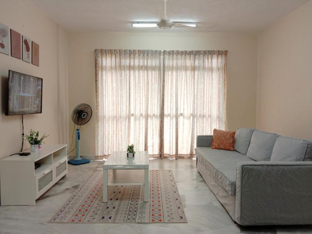 a living room with a couch and a table at Rafflesia Two Bedroom Pool View in Kampong Tanah Merah