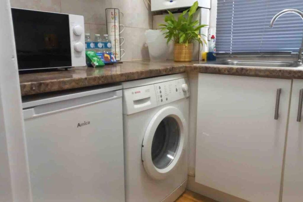 a kitchen with a washing machine and a sink at Edgware Road Large Ground Floor Studio in London