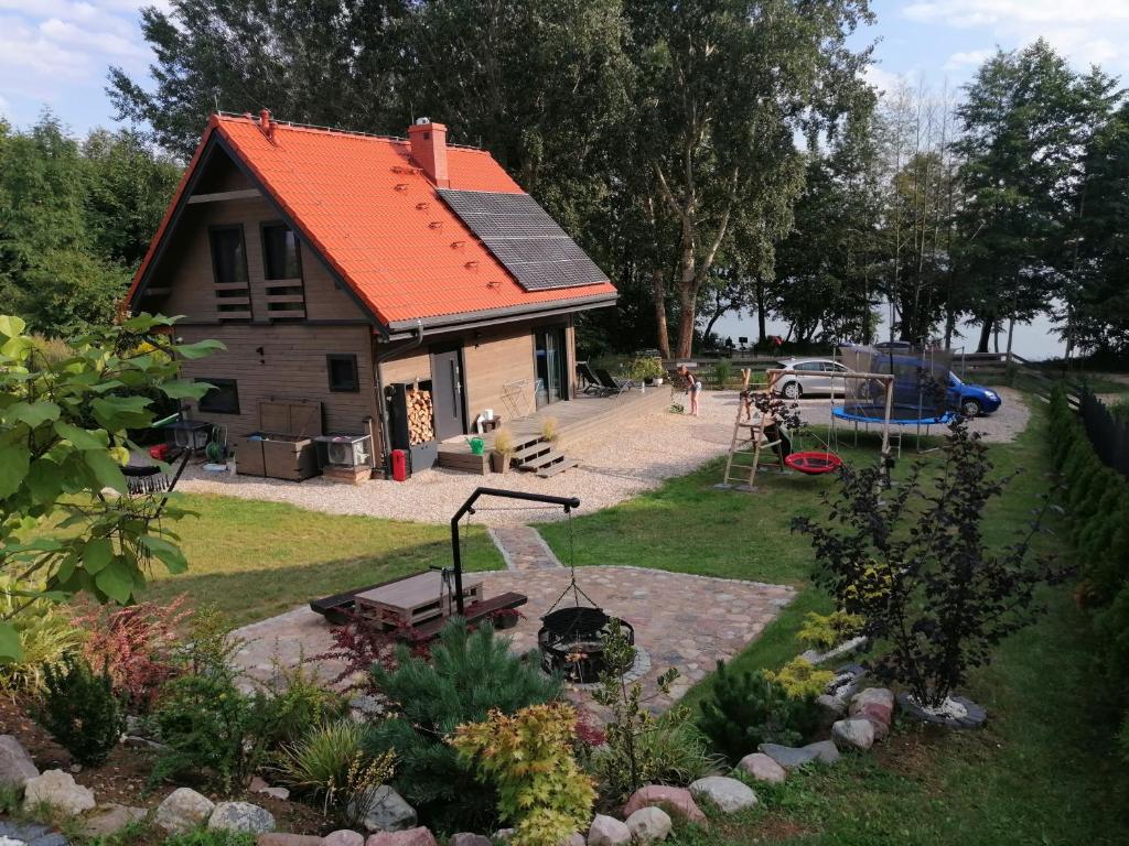 a small house with an orange roof and a backyard at Mazurska Widokówka in Węgorzewo