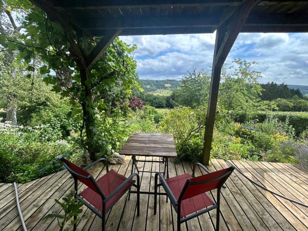 a wooden deck with chairs and a table with a view at Au mont des Brumes in Stoumont