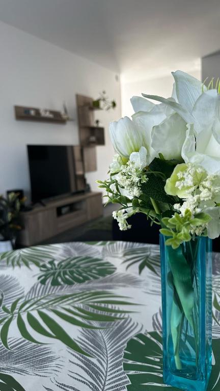 a blue vase filled with white flowers on a table at Belle Apartman in Balatonlelle