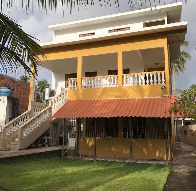 a yellow house with a balcony and a staircase at Casa de Japaratinga in Japaratinga
