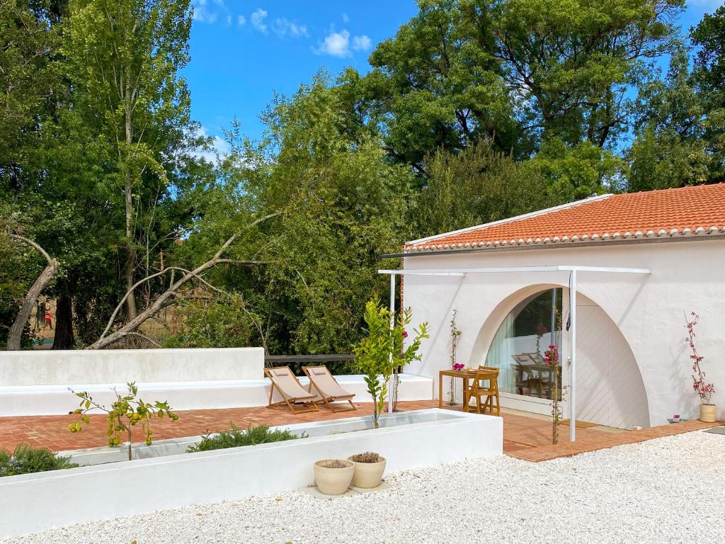a backyard with a white building and a patio at Casa do Rio in Leiria