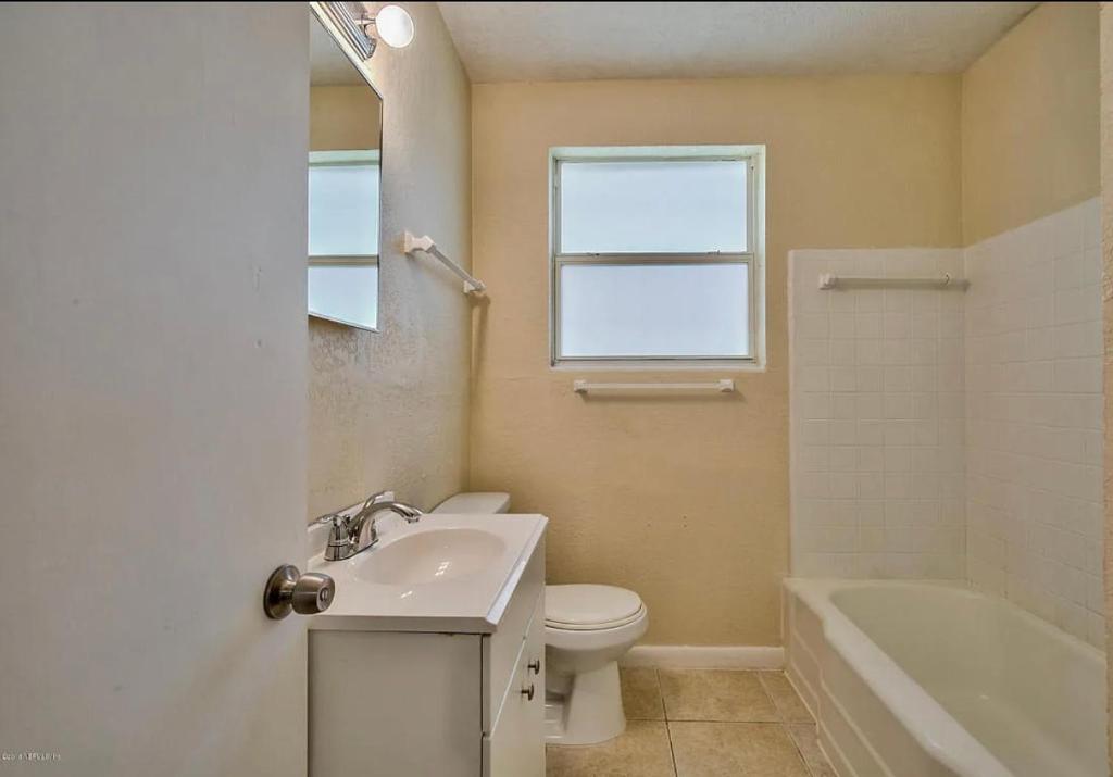 6515 Bartholf Ave في جاكسونفيل: حمام مع حوض ومرحاض وحوض استحمام