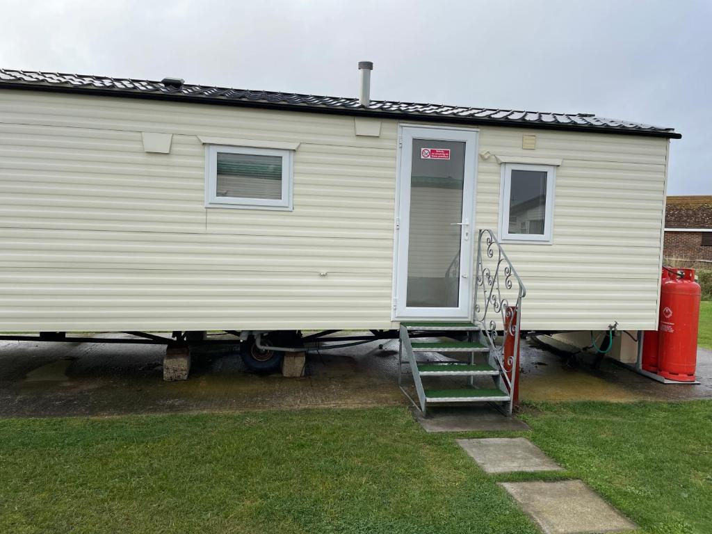a large white house with a staircase in front of it at Emeralds caravan lettings in Selsey