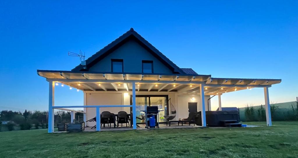 a house with a pergola in a field at Dom nad morzem z Jacuzzi 10 osób Morze Przygód in Mieroszyno