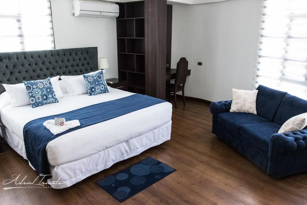 Domani Hotel Boutique في كوتشابامبا: غرفة نوم بسرير كبير وأريكة زرقاء