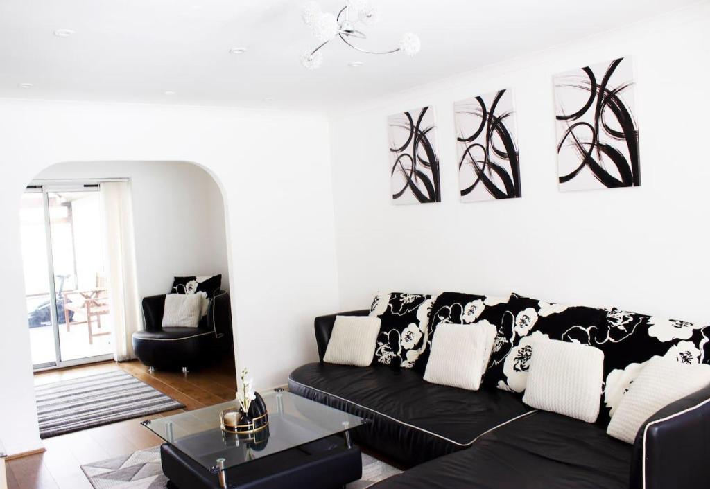 a living room with a black couch and a table at Spacious 4 Bed Home in Milton Keynes -free parking in Milton Keynes