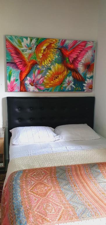 1 dormitorio con 1 cama con una pintura en la pared en Coffee House Minca, en Minca