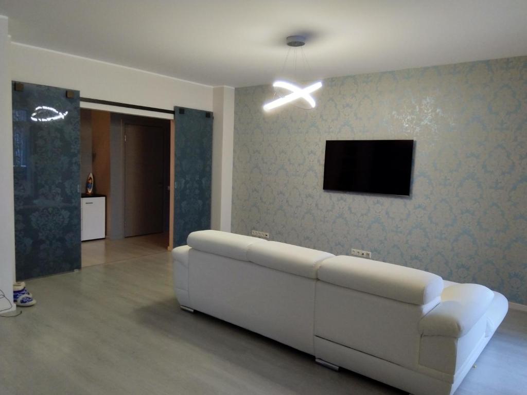 een woonkamer met een witte bank en een tv bij Liesmas in Rīga