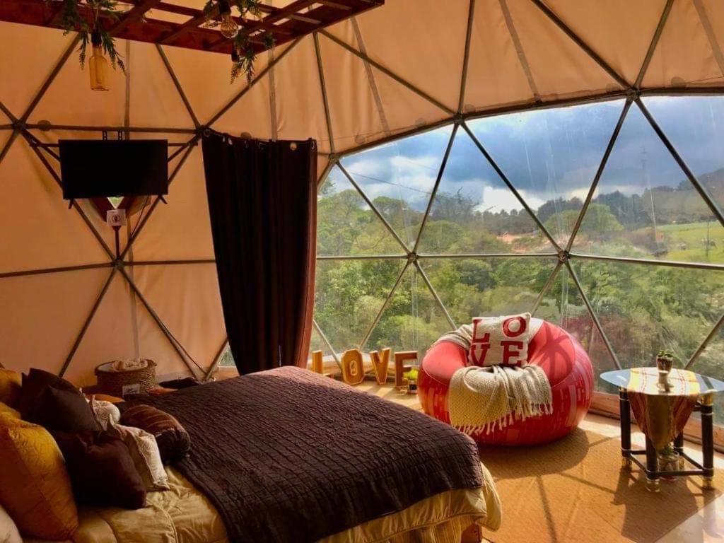 a bedroom in a yurt with a large window at Poas Volcano Observatory Lodge & Glamping in Poasito