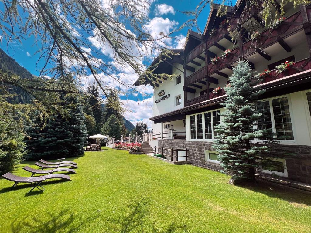 a lawn with lounge chairs in front of a building at B&B Garni Villa Campitello in Campitello di Fassa