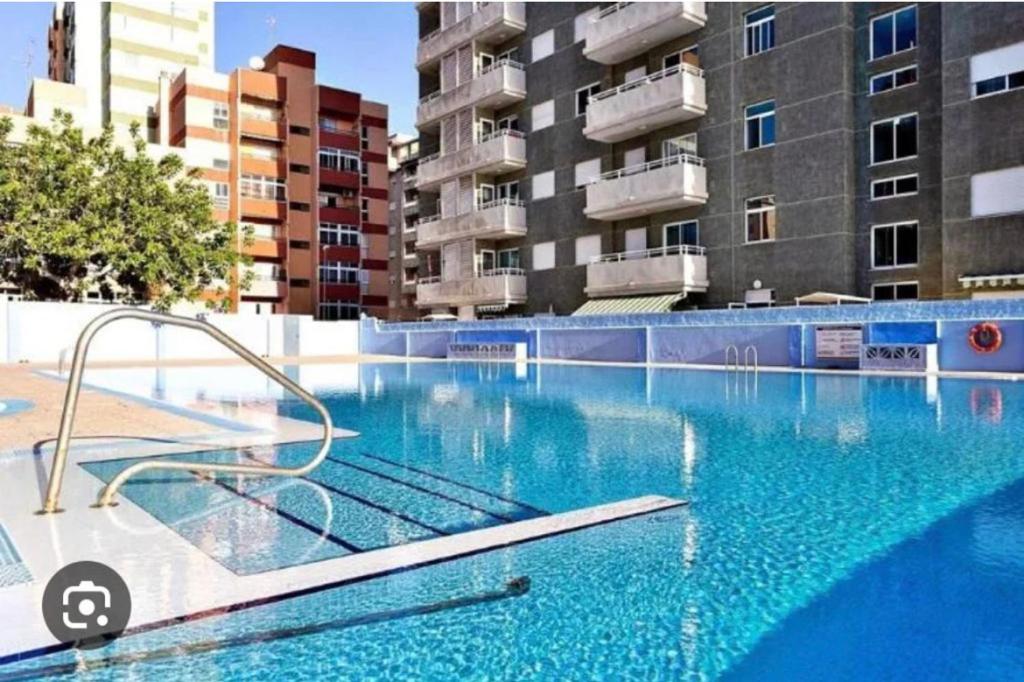 a swimming pool with blue water in front of a building at ApartBeach Wyliana in Candelaria