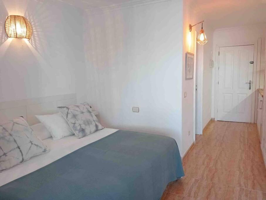 a white bedroom with a bed and a wooden floor at Apartamento golf del sur in Santa Cruz de Tenerife