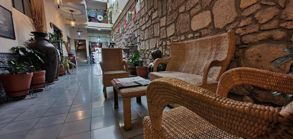 a room with wicker chairs and a stone wall at ROSA BARROCO in Morelia