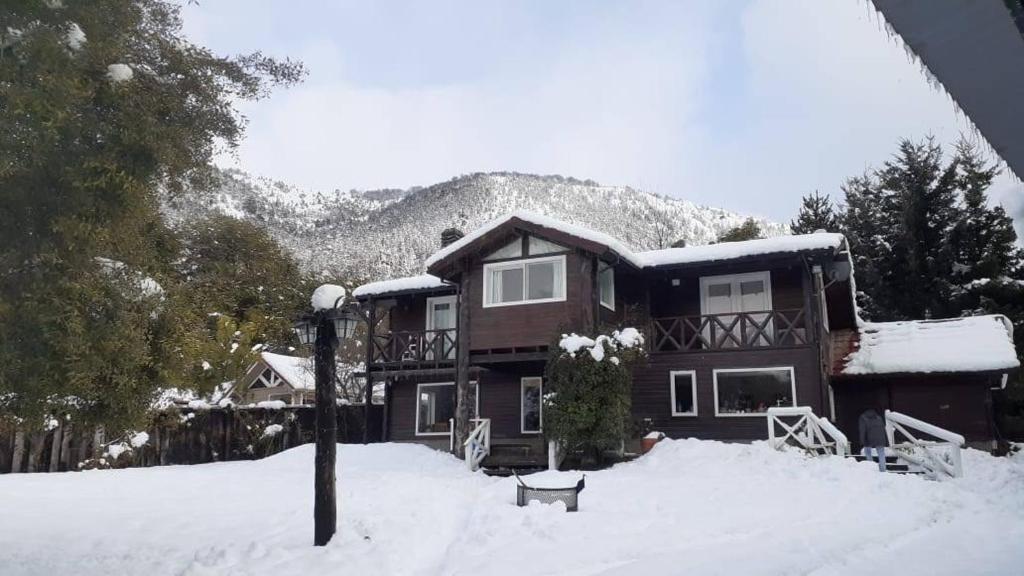 una casa grande en la nieve con una montaña en INDÓMITO HOSTEL en San Carlos de Bariloche
