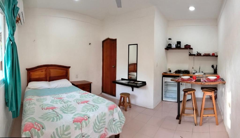 a bedroom with a bed and a small kitchen at Posada los abuelos in Holbox Island