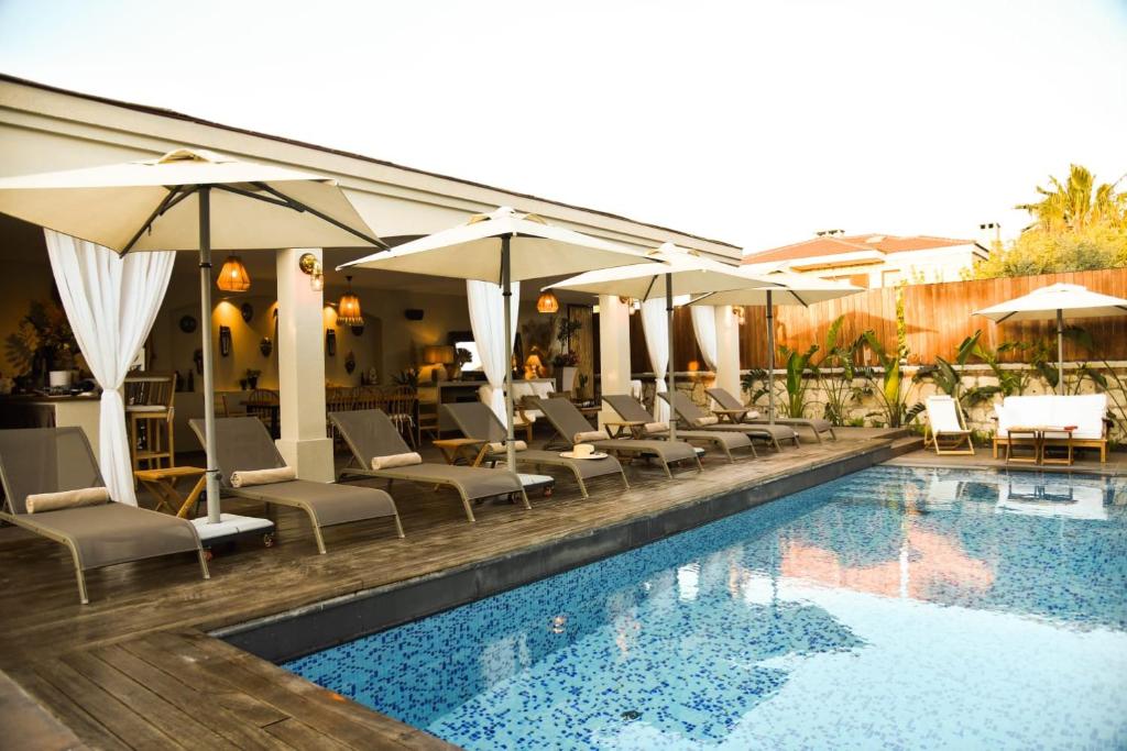 a swimming pool with lounge chairs and umbrellas at Soas Suites in Alacati