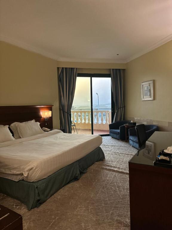 a hotel room with a bed and a large window at فندق حدائق فرسان الفندقية in Ḩumr