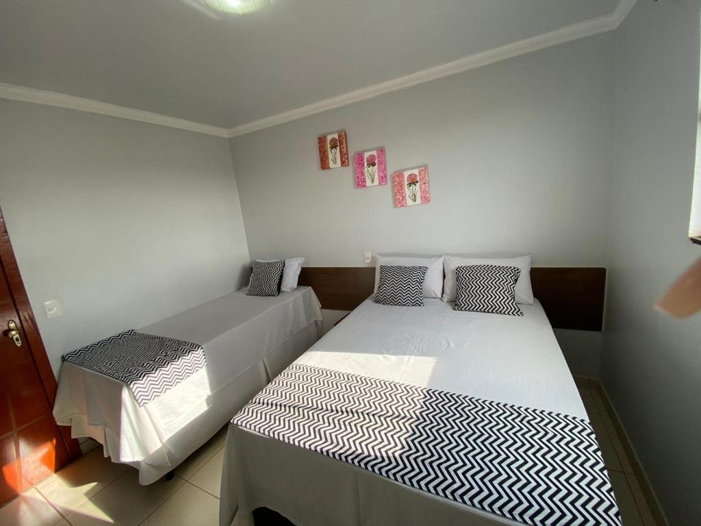 a bedroom with two beds and two pictures on the wall at Hotel Uirapuru in Alexânia