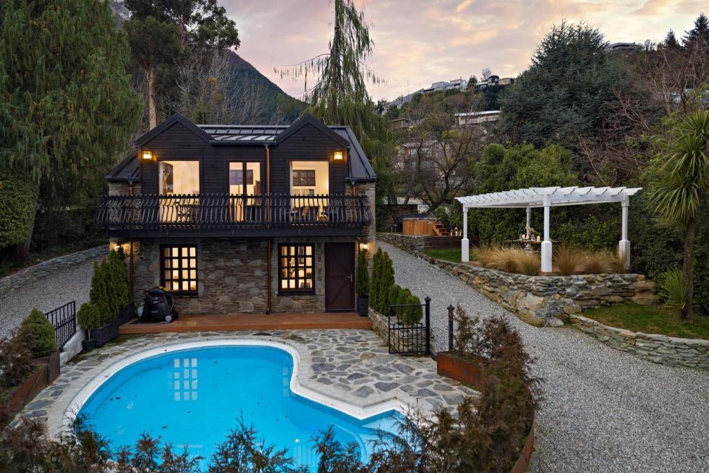 ein Haus mit einem Swimmingpool vor dem Haus in der Unterkunft Alpine Cottage in Queenstown