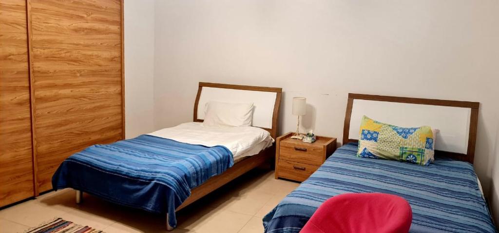 1 dormitorio con 2 camas y silla roja en Flat One Room Apartment Talabay Aqaba, en Al Burj