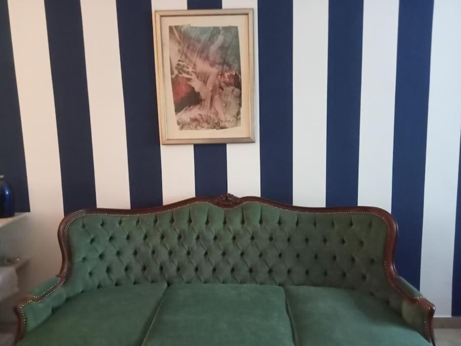 a green couch in a room with blue and white stripes at Il grande blu in Milan
