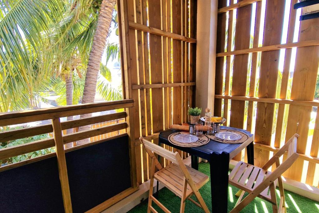 a table and chairs on a balcony with a palm tree at Le Ti Nid house - ch Papangue, résidence avec piscine commune in Saint-Denis