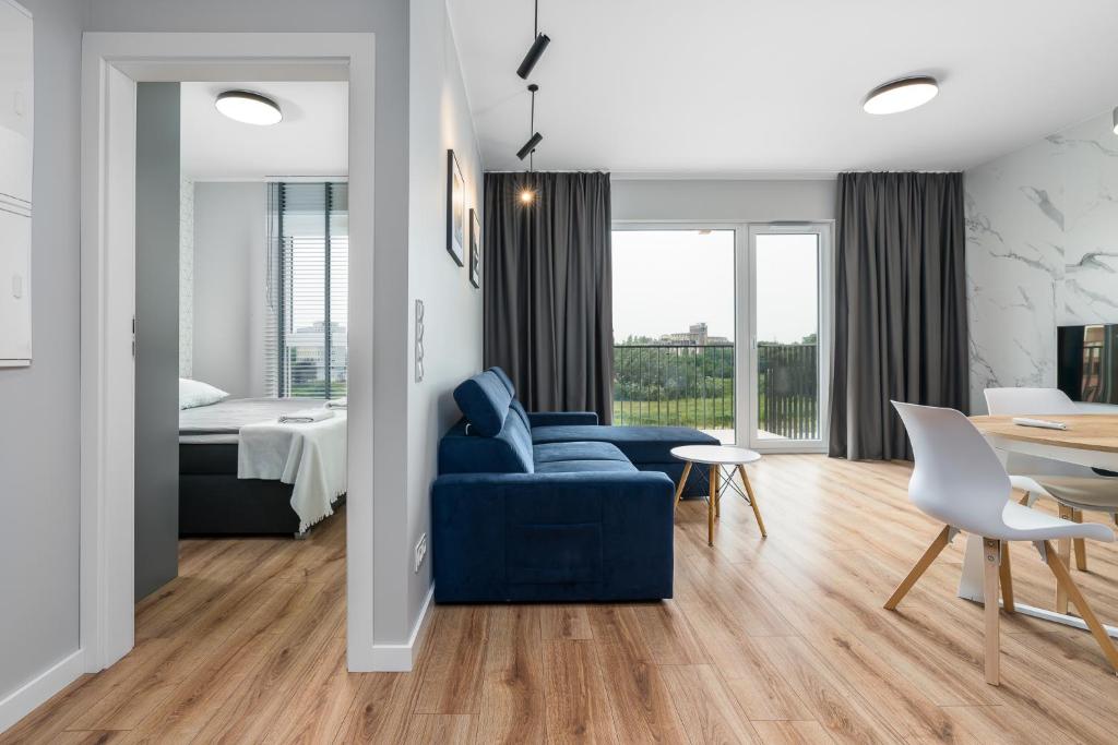 a living room with a blue couch and a bedroom at Riverside Apartments by KRAMM in Poznań