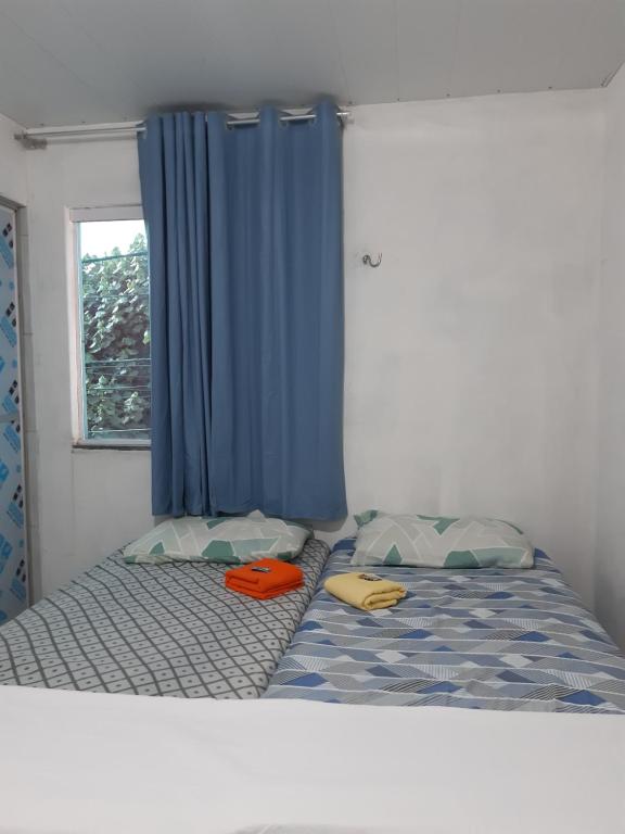 a bed with two pillows and a blue curtain at Pousada do Joaquimxdarc in Natal