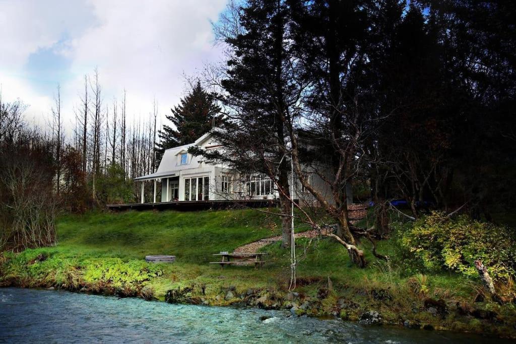 a house sitting on top of a hill next to a river at Riverfront Paradise Villa in Hveragerði