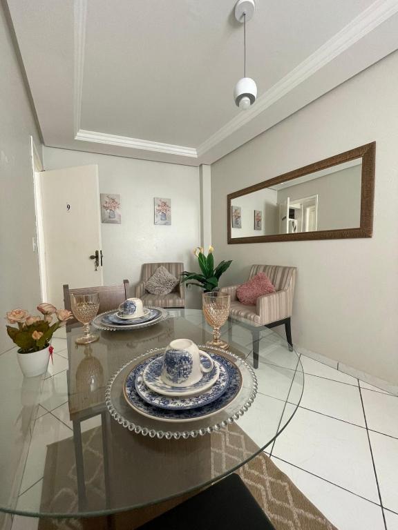 sala de estar con mesa de cristal y espejo en Apartamento Encantador Central, en Montes Claros