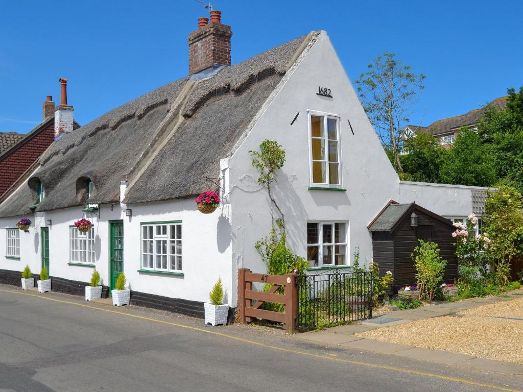 a white cottage with a thatched roof at The Brambles in Horning