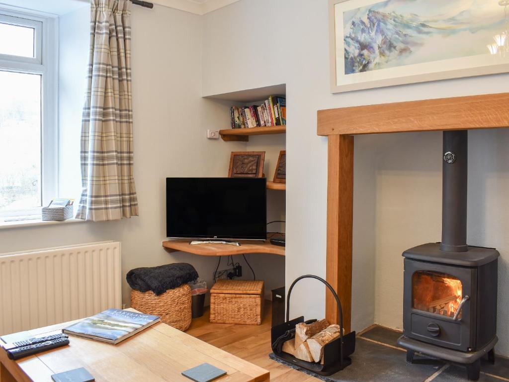 a living room with a wood stove and a desk at Hovera in Glenridding