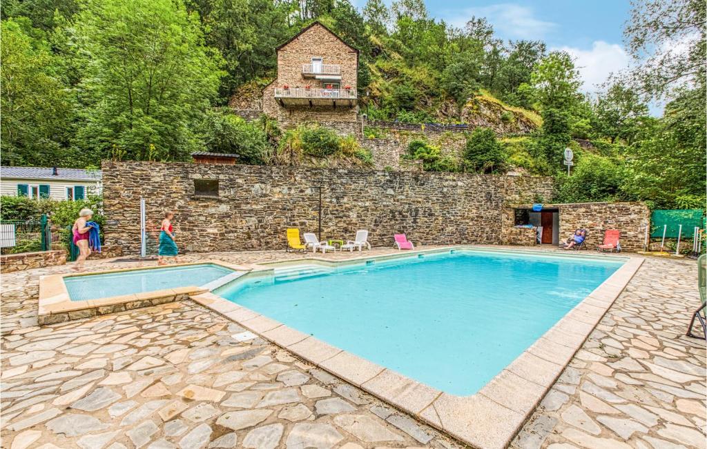 Conques-en-Rouergue的住宿－Cozy stacaravan In Conques-en-rouergues With Kitchen，一座游泳池,位于一座带房子的石墙前