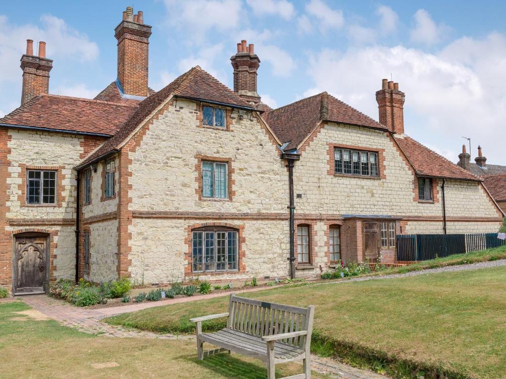 un banco frente a un gran edificio de ladrillo en Stable Yard Cottage en Selborne