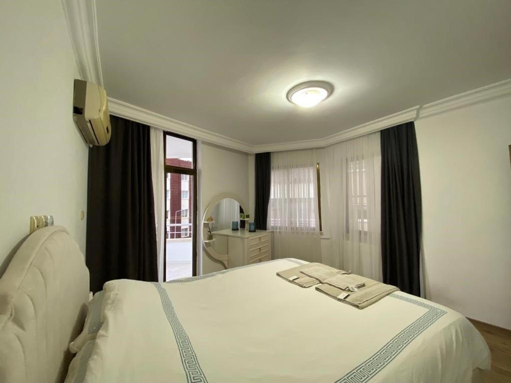 a bedroom with a white bed and a mirror at Luxury apartment with sea view in Mezitli