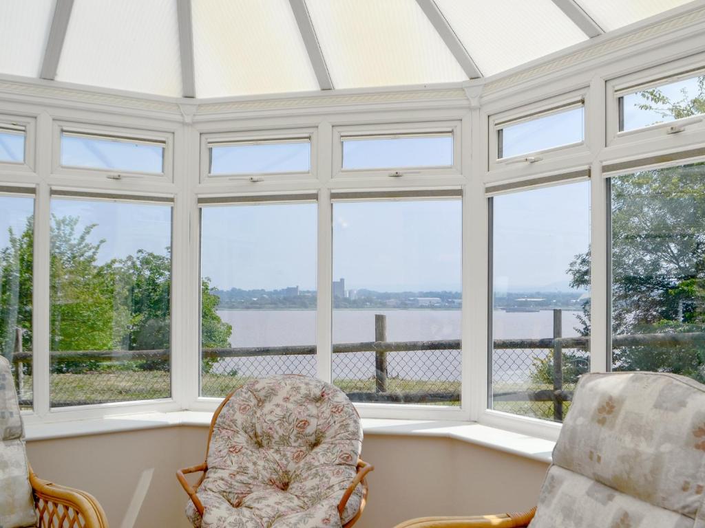 a conservatory with windows and chairs and a view of the water at The Coach House in Lydney