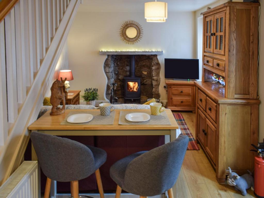 a living room with a table and chairs and a fireplace at Christill Cottage in Burneside