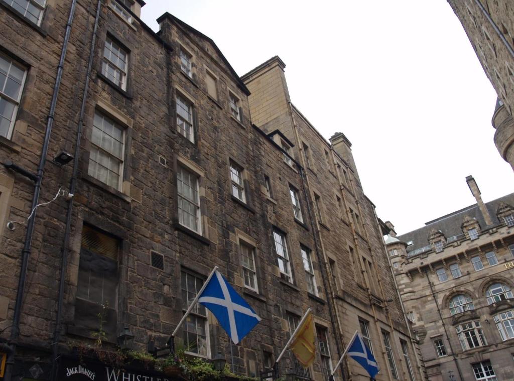 um grande edifício de tijolos com bandeiras à frente em Niddry Street Apartments Edinburgh em Edinburgo