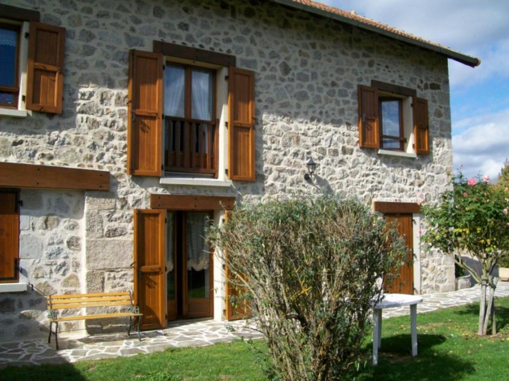 ein Steinhaus mit Holzfenstern und einer Bank in der Unterkunft Gîte Vitrac, 3 pièces, 4 personnes - FR-1-742-450 in Vitrac