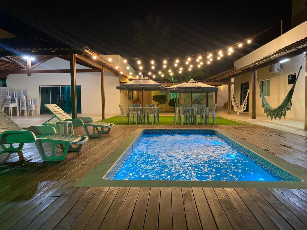 a swimming pool with tables and chairs and lights at Casa de praia Le Frute. Mar, piscina, descanso! in Vila Velha
