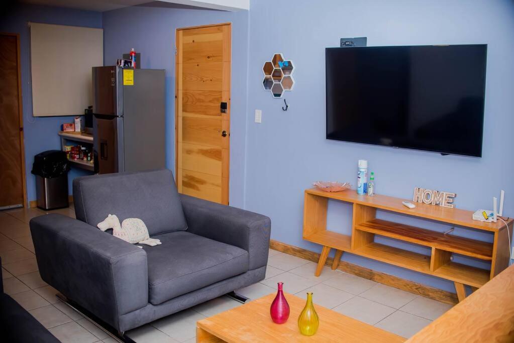 Una sala de estar con un sofá y un televisor en una pared. en Departamento Colima, en La Paz