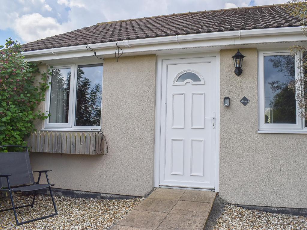 ein Haus mit einer weißen Tür und einem Stuhl in der Unterkunft Mallard Cottage - Uk33872 in Cote
