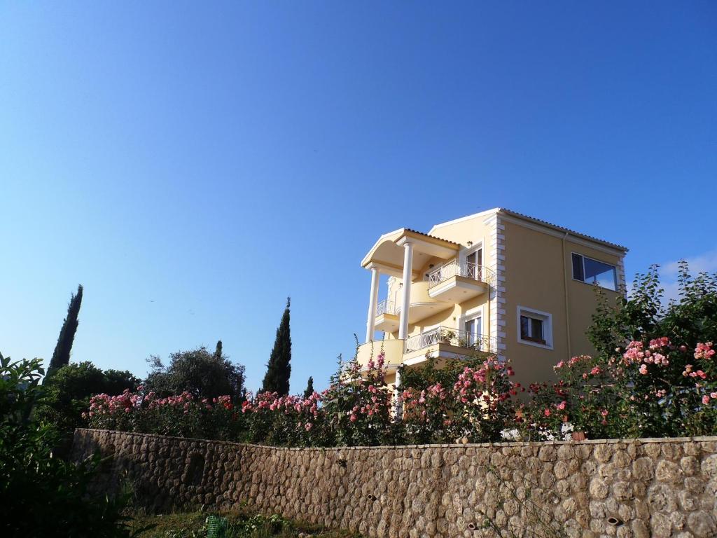 a house behind a stone wall with flowers at Linda House Corfu in Gastouri