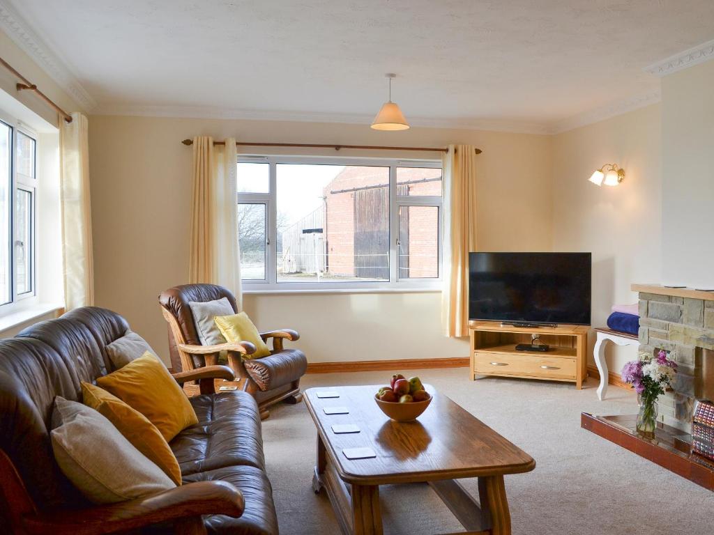 sala de estar con sofá de cuero y TV en Ivy Grange Cottage, en Wistow