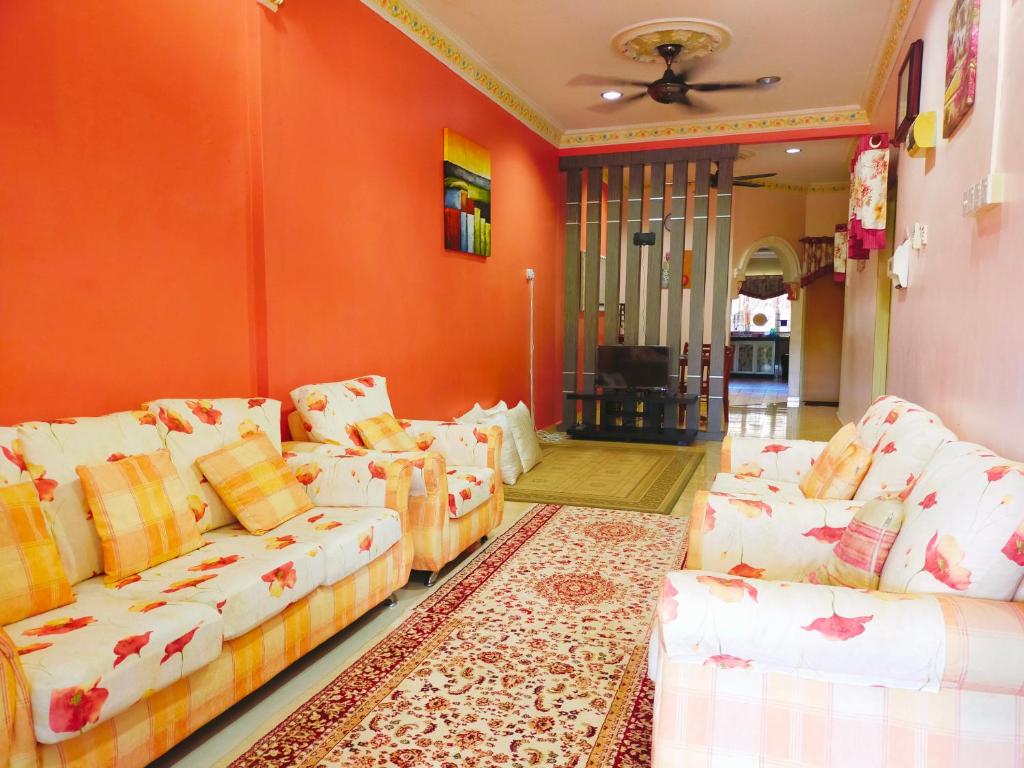 a living room with orange walls and white couches at D'LAILA HOMESTAY in Kampong Gelegoh Lama