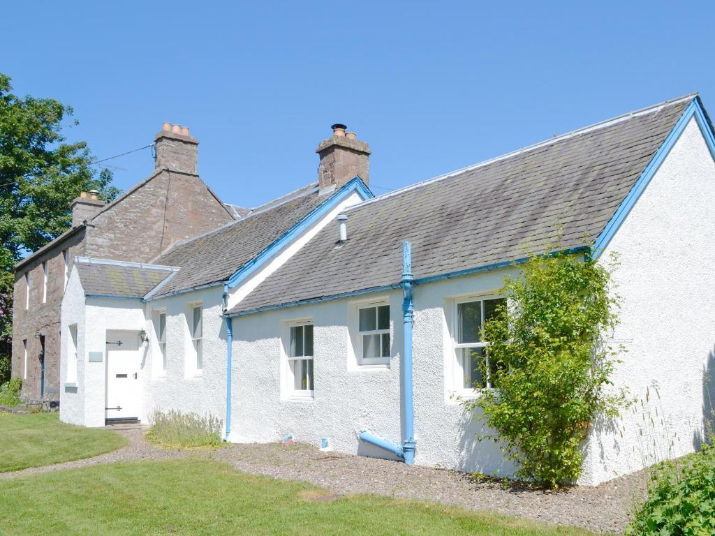 Casa blanca con techo azul en The Old School House Cottage, en Coupar Angus